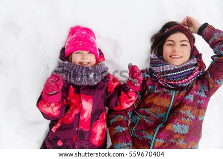 Mother ,daughter lying on snow