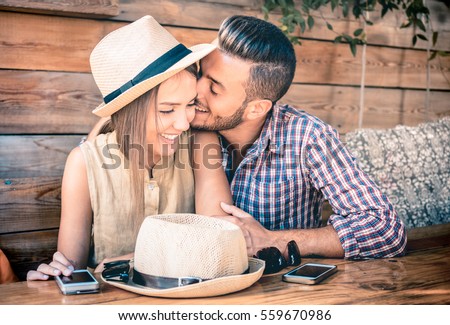 Young fashion couple of lovers at beginning of love story - Handsome man whispers kisses in pretty woman ear - Relationship concept with boyfriend and girlfriend together - Warm retro filter Royalty-Free Stock Photo #559670986