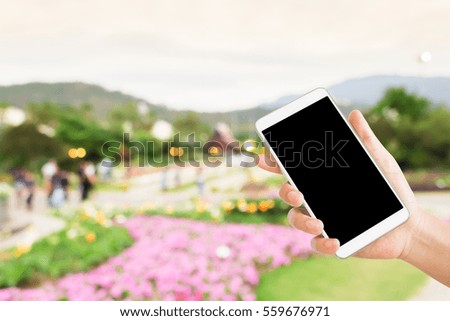 woman use mobile phone and blurred image of people in the park , in the evening