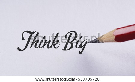 "Think big" words written on white paper using red pencil with selective focus and depth of field (dof) - education, business and finance concept