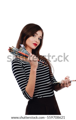 Cute beautiful girl artist holding a palette and a brush in the process draws inspiration. White background, isolated. Red lips, long hair brunette. Art femininity concept.