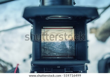 look at the mountain scenery through the viewfinder of an old film camera