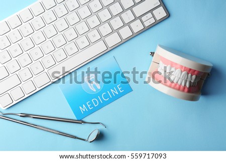 Business card, keyboard and dental tools on blue background. Medical service concept