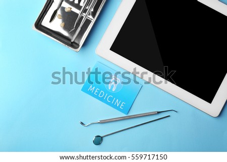 Business card, tablet and dental tools on blue background. Medical service concept