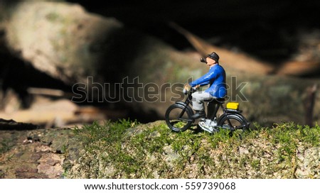 Miniature tiny toys cyclist ride bicycle on the tree branch