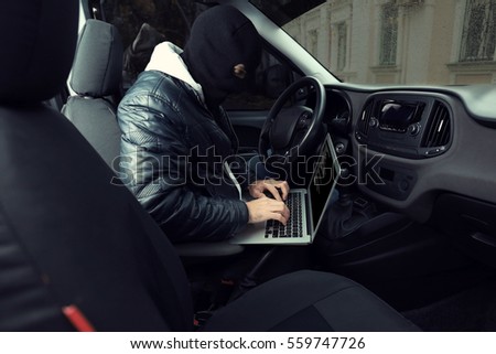 Car thief hacking security systems with laptop computer