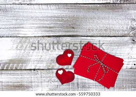 Red note cards and envelopes tied in string with wooden hearts on whitewash rustic antique wood background; Valentine's Day, Christmas and love concept with white copy space