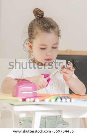 Beautiful little girl cutting paper with scissors on the art lesson class. Children education concept. Kids crafts. Learn Study Education School Knowledge Concept