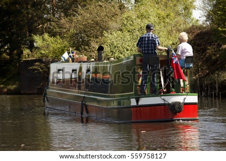 Aged couple on narrow boat in canal, England Royalty-Free Stock Photo #559758127