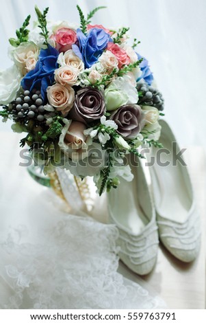 Wedding.Decor. Artwork.Bride's bouquet with blue,white,and grey flowers and white shoes lie on table