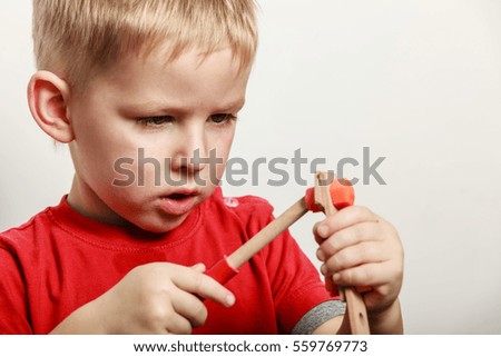 Spending free time play and education for children. Little boy in red shirt play with toy wood screwdriver.