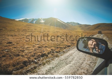 Traveler photographer man make a picture through car window into the mountains. 