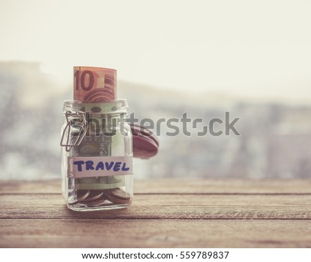 jar with money on wooden table next to window. holiday savings