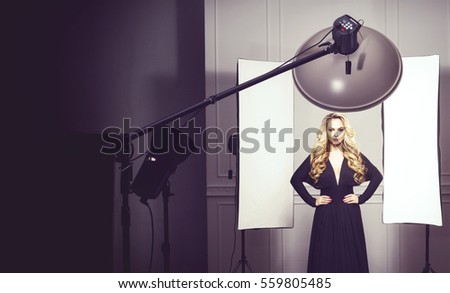 Beautiful and attractive model in black dress. Backstage shooting. Fashion, beauty, glamour concept.