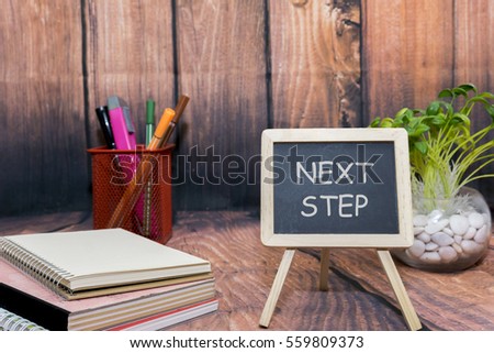 mini blackboard with text, book and wooden background