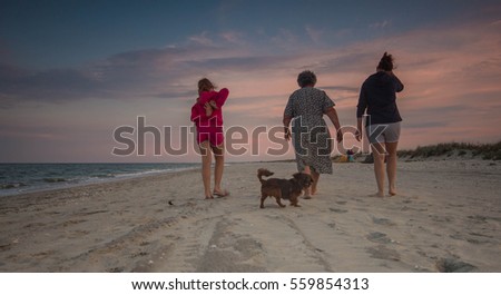 Generations in the family, picture showing three generation of women and a dog walking on the beach.