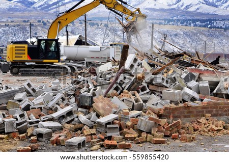 Heavy equipment being used to tear tearing down building construction Royalty-Free Stock Photo #559855420