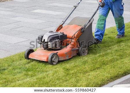 Mowing the lawn in the park, cutting the grass. Selective focus and motion blur.
