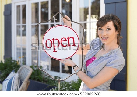 Woman hanging open sign on frame