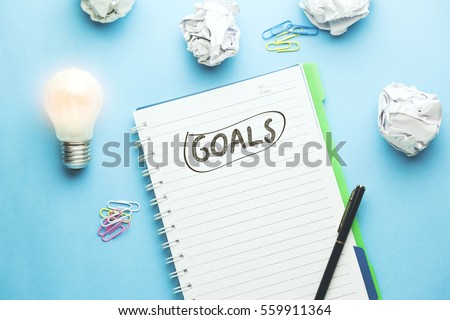 goals text on notebook with idea on blue background Royalty-Free Stock Photo #559911364