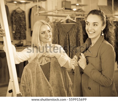Beautiful young female customers selecting coats and jackets at the store. Focus on the right woman