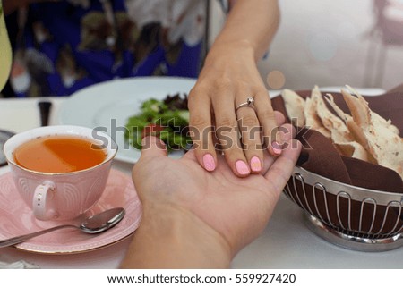 Picture of man holding his girlfriend's hand with engagement ring on finger at the restaurant. Proposal concept.