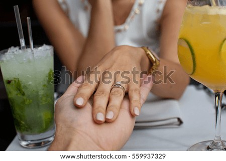 Picture of man holding his girlfriend's hand with engagement ring on finger at the restaurant. Proposal concept.