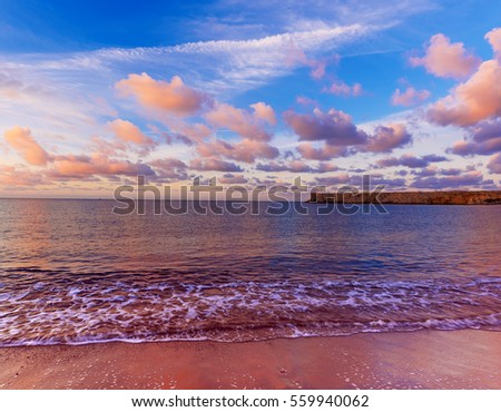 Beautiful colorful sunrise at the sea with dramatic pink clouds over blue sky and soft waves. Beauty world natural outdoors travel background