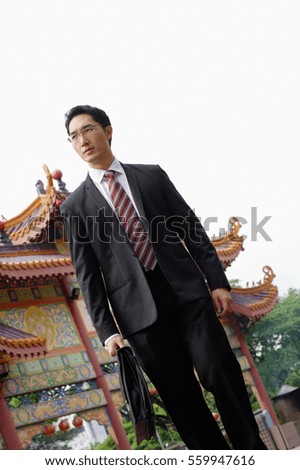 Businessman carrying briefcase, Chinese temple in the background