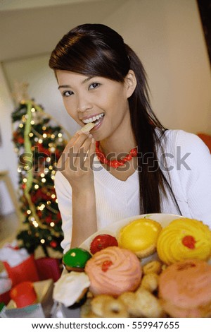 Woman eating a cookie, holding plate of food
