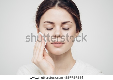 Girl with closed eyes and face wipes clean skin with a cotton pad Royalty-Free Stock Photo #559959586