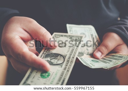 Man giving one us dollar banknote and holding cash in hands. Money credit concept. Toned picture.