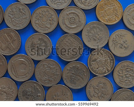 Many One Pound (GBP) coins, currency of United Kingdom (UK) over blue background