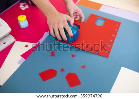 Young woman make scrapbook of the papers on the table using tools for cutting paper. Hand made photo album.Shallow depth of field