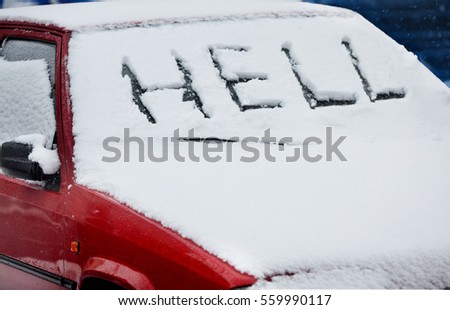 Word "hell" is written on the snow-covered car windshield