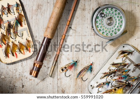 Fly fishing rod, reel and vintage salmon flies in boxes on a distressed white wooden background Royalty-Free Stock Photo #559991020
