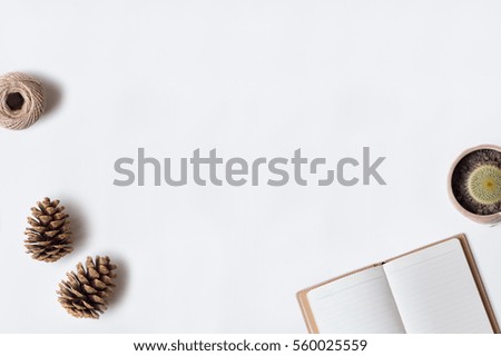 White office desk table with open diary, cactus, rope, and pinecones. Top view with copy space, flat lay.