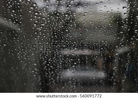 The falling rain drops on the front glass of any car