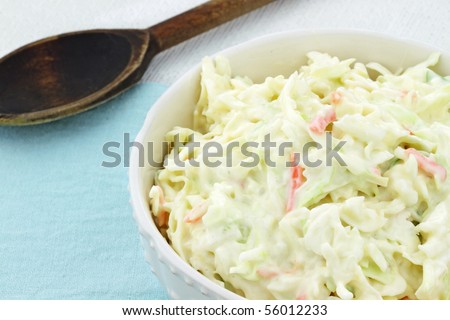 Homemade coleslaw in a white bowl with an old wooden spoon in the background. Royalty-Free Stock Photo #56012233