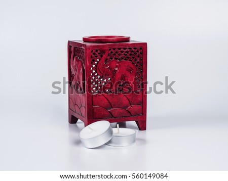Picture of a red aroma lamp with two candles on white background. Aroma lamp made of stone. Elephant carved on aroma lamp.