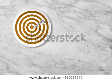 Dart arrow hitting in the target center of dartboard on white marble background. Bulls eye is a target of business. Dart is an opportunity and Dartboard is the target.