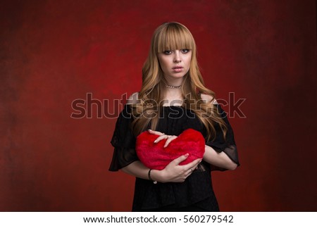 girl on a red textured background with a toy heart