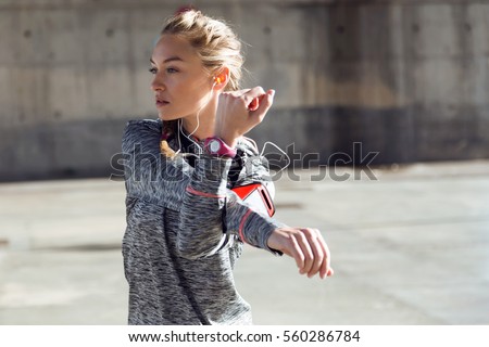 Portrait of fit and sporty young woman doing stretching in city. Royalty-Free Stock Photo #560286784