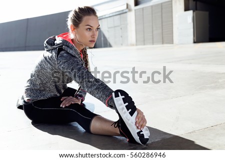 Portrait of fit and sporty young woman doing stretching in city. Royalty-Free Stock Photo #560286946