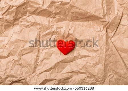 Red velvet heart on wrinkled old vintage brown paper as background texture Valentines day concept Top view