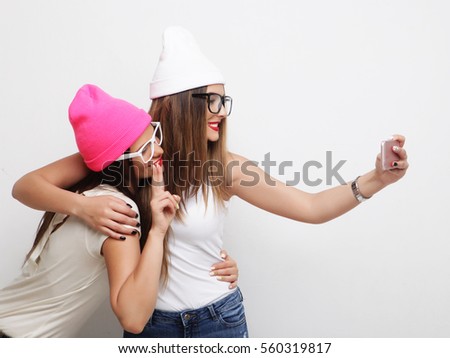 Two teenage girls friends in hipster outfit make selfie on a phone. 