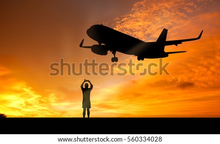 Silhouette of man posing for photo on the beach at sunset with an airplane landing.