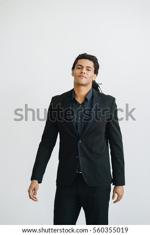 Happy young businessman in black suite and blue shirt standing over white background. Portrait of a handsome man. Color