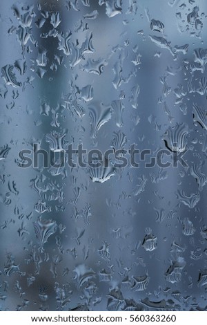 Drops of rain on the window, rainy day, blurry fence in the background. Shallow DOF