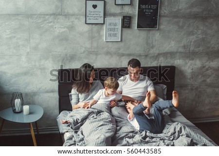 Mother, father and two sons  on the bed. Christmas. Royalty-Free Stock Photo #560443585